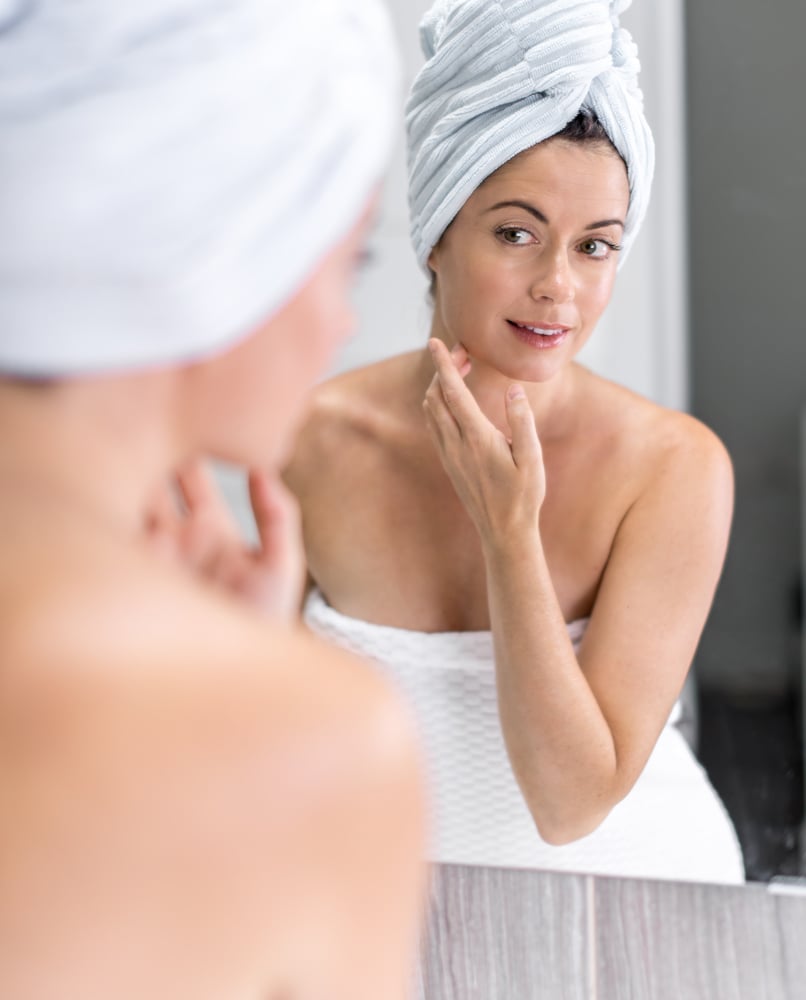 Attractive middle aged woman looking in the mirror