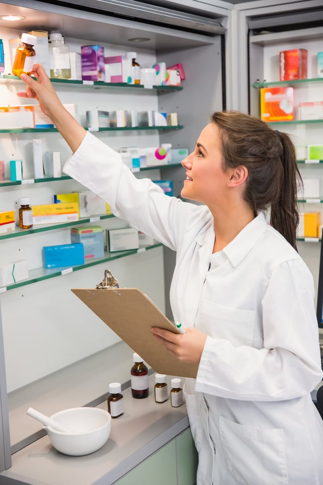 Junior pharmacist taking medicine from shelf at the hospital pharmacy